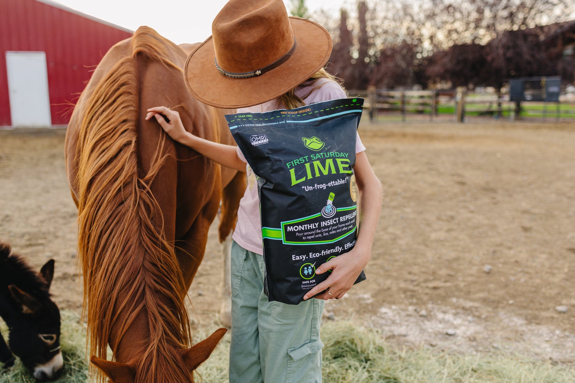 A younger girl holding a bag of First Saturday Lime and standing with a horse.