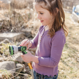Child holding a garden hose nozzle outdoors