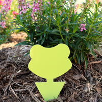 A new green gnat trap stuck in the mulch of a garden bed.