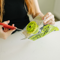 Person using scissors to open a package of Superfly Catcher fly traps on a white surface.