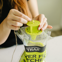 Person threading twine through the top of a  'First Saturday Trap' Super Fly Catcher.