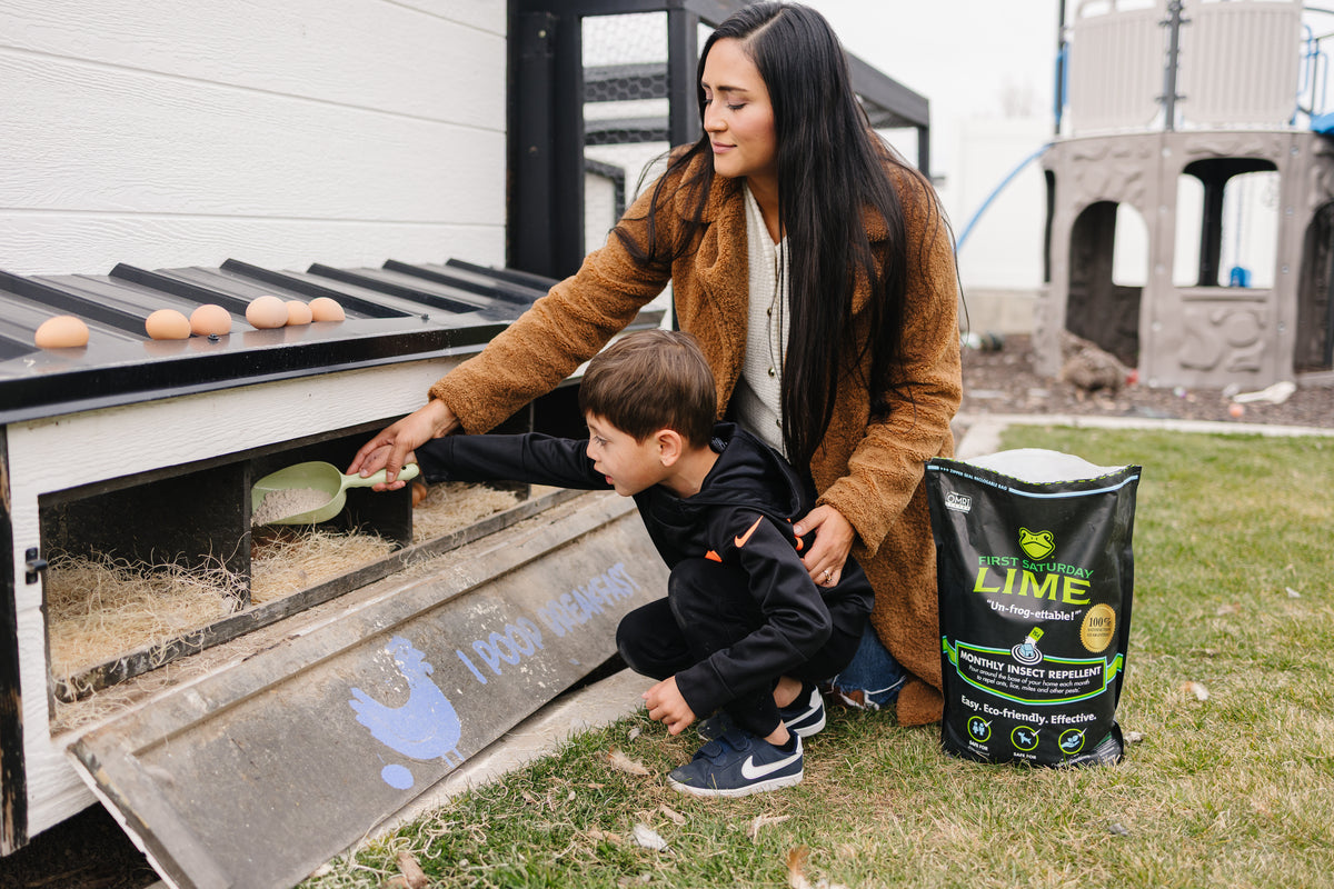 A woman helps a young boy pour First Saturday Lime onto the bedding of a chicken coop.